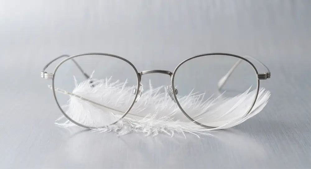 Ultra-thin titanium glasses resting on a feather to demonstrate the lightest glasses frames available.
