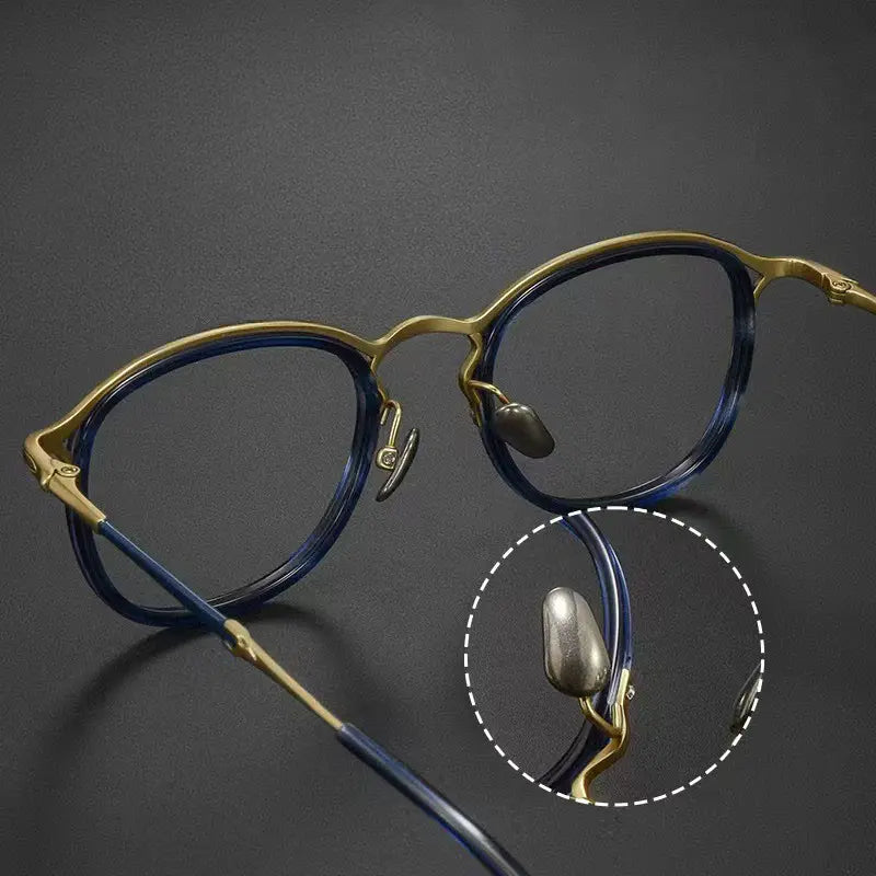 Round Vintage Designer Eyelasses from Verhalo Vision with a gold-tone frame and dark blue acetate detailing, shown on a dark gray background with a circular inset highlighting the hinge and pure titanium nose pad area.