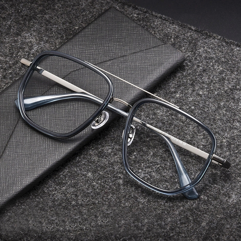 Square titanium avitor eyeglasses with a dark gray frame and gray temples, resting on a textured gray surface next to a matching gray case.