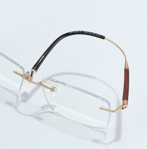 Pair of rectangle rimless titanium  glasses with gold frame and wooden accents on a light gray background | Verhalovision