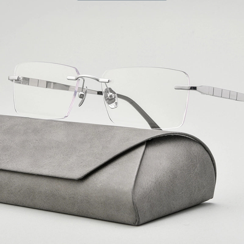 minimalist silver titanium rimless spectacles for men with silver titanium temples resting on a gray textured case against a light gray background.