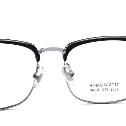 Close-up of a pair of titanium square browline magnetic frame glasses with a black acetate top frame, thin silver titanium lower rims, and clear nose pads on a white background. The inside of the right lens shows the text 'TITANIUM 54-18-148'.